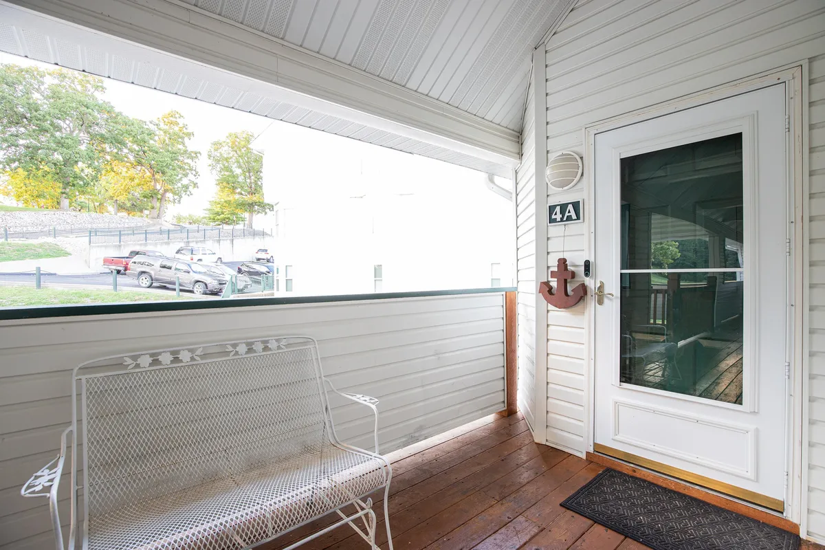 The image shows a welcoming front entrance with a white bench and anchor decor, leading into the home. The area is bathed in natural light, inviting guests to relax, enjoy the view, or greet friends and family as they arrive.