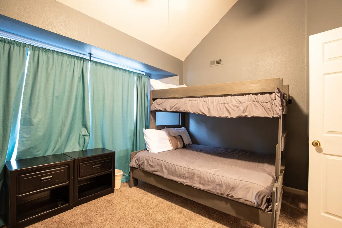 A cozy loft area with a bunk bed, curtains for privacy, and bedside nightstands. The setup is playful yet practical, making it ideal for children and teens to have their own designated retreat for sleeping or lounging.
