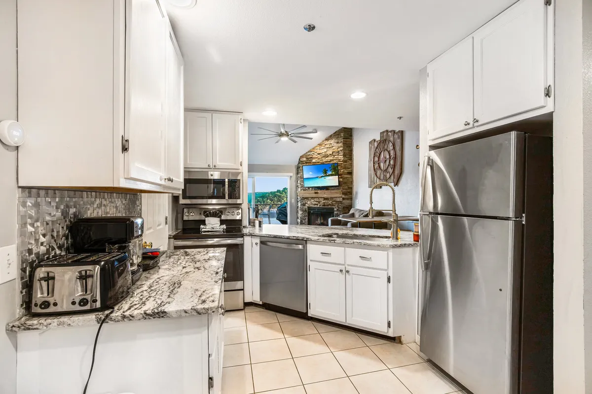A modern kitchen with granite countertops and stainless steel appliances flows seamlessly into the living area. The open layout invites easy movement between cooking, dining, and relaxing spaces, emphasizing the home's social hub. The kitchen’s sophisticated design showcases updated appliances and bar seating ideal for shared meals and celebrations.